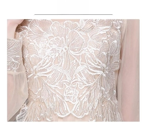 Gros plan sur un tissu en maille champagne avec broderie florale et sequins scintillants