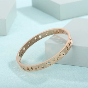 Macro view of rose gold hollow star bangle with polished finish on blue geometric blocks