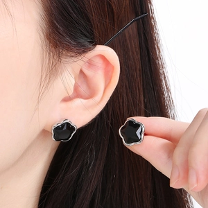 Close-up of elegant black five-pointed star earrings with a polished silver-tone base