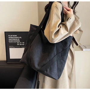 Detail of a large black canvas tote bag showing thick material and minimalist shoulder strap