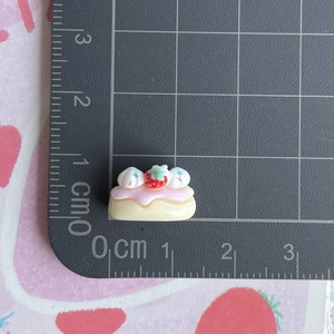 Close-up of a tiny strawberry cake resin charm showing 1.5cm size on a scale