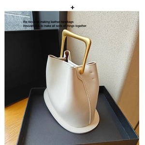 Minimalist white leather bucket bag with wood handle in a luxury gift box packaging