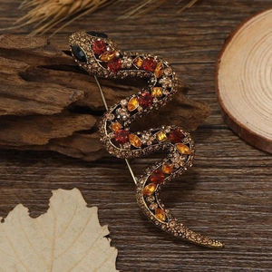 Macro shot of retro rhinestone snake brooch on a vintage wood and maple leaf background