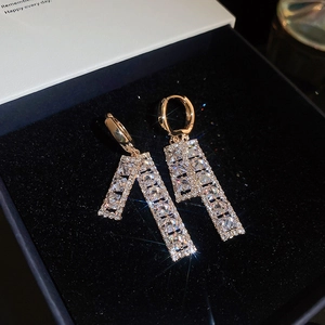 Macro detail of gold geometric earrings with pavé set cubic zirconia on dark velvet