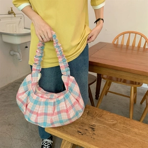Close-up of pink and blue checkered tote bag with ruffled handles in a retro indoor setting