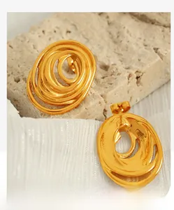 Detail of gold spiral layered hoop earrings on a textured stone surface with natural light