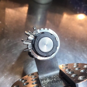 Precision silver titanium steel gear-shaped jewelry component on a professional bench block
