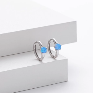 Macro shot of silver S925 earrings with blue opal stone on white geometric block