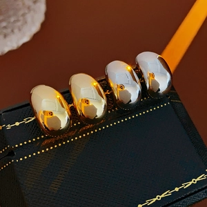 Close-up of gold and silver metallic bean earrings on a luxury dark blue jewelry tray