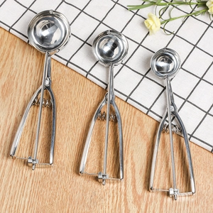 Three sizes of stainless steel ice cream scoops with trigger release on a wooden table