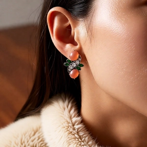Detail of vintage resin earrings with pink stone and green leaf inlay on model
