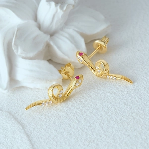 Macro view of S925 silver cobra stud earrings with red gemstones and sparkling white stones