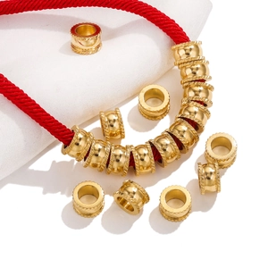 Macro shot of gold stainless steel textured spacer beads on a red cord for DIY jewelry