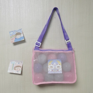 Close-up of pink mesh shell bag with purple adjustable strap and cute cartoon card inside