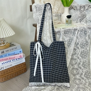 Close-up of black and white checkered tote bag with white lace trim and bow detail