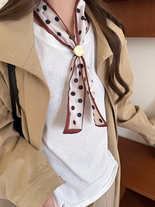 Close-up of elegant polka dot silk scarf with a golden metal ring buckle on a model