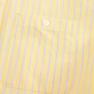 Detail van het geel en wit gestreepte poplin overhemd met borstzak en witte knoop