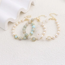 Detailed close-up of three beaded bracelets in blue, green, and cream with gold lobster clasp