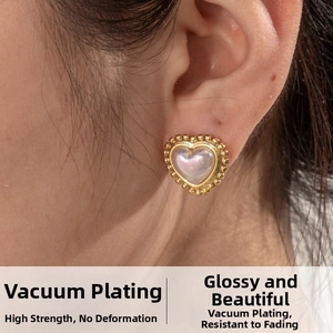 Macro view of gold-plated heart earring with iridescent center on ear lobe