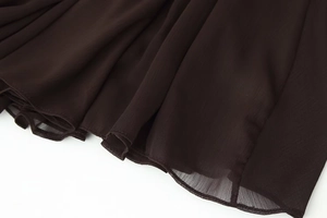 Macro shot of dark brown sheer chiffon fabric with detailed pleated stitching and overlock edge