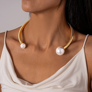 Detailed close-up of golden spiral torque necklace featuring two asymmetrical white pearls