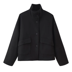 Detail of black wool jacket featuring stand collar, large utility pockets and button closure