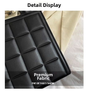 Macro shot of black quilted faux leather with large square stitching and fine edge seams