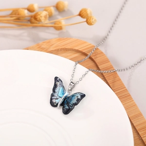 Macro detail of butterfly pendant necklace with blue-black gradient and gold glitter