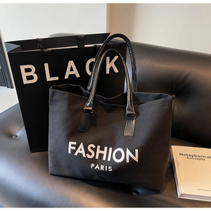 Detalle del bolso tote de lona negra con asas de cuero y estampado Fashion Paris