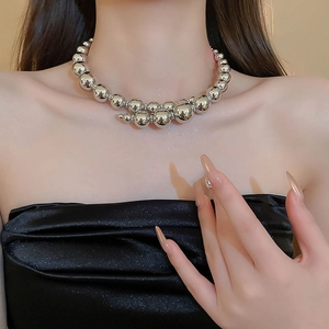 Close-up of minimalist silver metallic bead necklace worn by a model on a black top