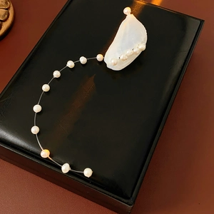 Detail of freshwater pearl and shell tassel earrings on black leather display case