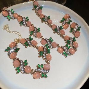 Macro detail of gold flower necklace and bracelet with pink and green crystal gems