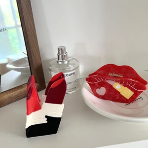 Creative acetate hair claws featuring red high heels and lip designs on a white table