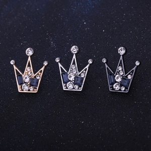 Detailed macro of crown lapel pins in gold, silver, and dark metal with blue crystals