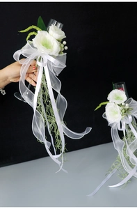 Detail of white artificial rose and long organza ribbon for wedding champagne glasses