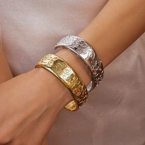 Detailed view of heavy metal cuffs with embossed scroll patterns in gold and silver finish