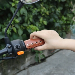 Close-up of brown vintage leather motorcycle handlebar grips with cross-lace detailing