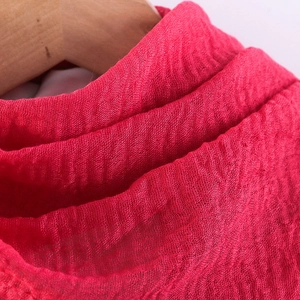 Macro shot of red crinkled cotton linen fabric texture on a wooden hanger