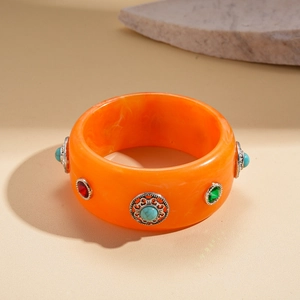 Detail of bohemian orange resin bangle with vintage silver patterns and colorful crystals