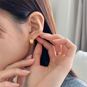 Detailed view of triple-layered gold hoop earrings with polished finish and wave ring