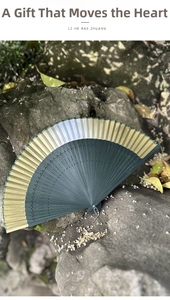 Detail of teal Chinese folding fan with hollow bamboo ribs on vintage stone background