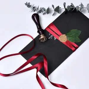 Deep red satin ribbon on black envelope with wax seal for gift wrapping and DIY crafts