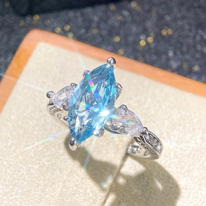 Macro view of marquise-cut sky blue stone ring with side pear-shaped accents on leather stand