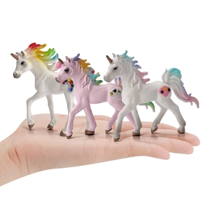 Three miniature rainbow unicorn figurines held in hand showing detailed small scale sizes