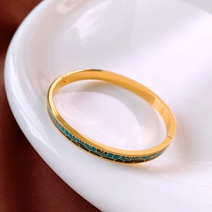 Détail du bracelet en titane doré avec motifs géométriques en émail vert et noir