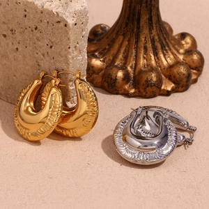 Chunky gold and silver waterdrop earrings with a polished mirror finish on travertine stone