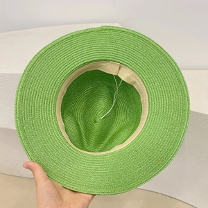 Detailed close-up of grass green straw hat interior with adjustable strap and woven texture