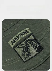 Close-up of the AIRBORNE embroidery and twill fabric texture on a camouflage hat