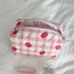Detail of pink strawberry checkered quilted makeup bag with zipper and soft cotton texture