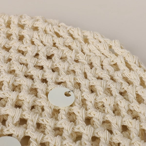 Close-up of cream knit fabric with hollow mesh structure and white paillette sequins